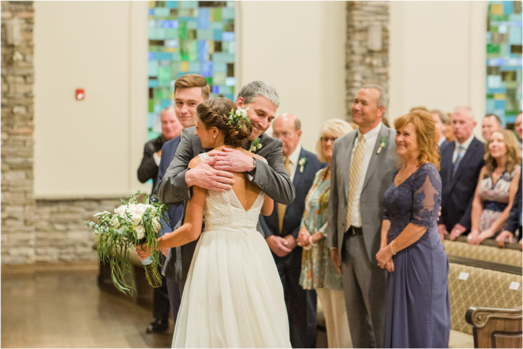 Father hugs his daughter at the alter